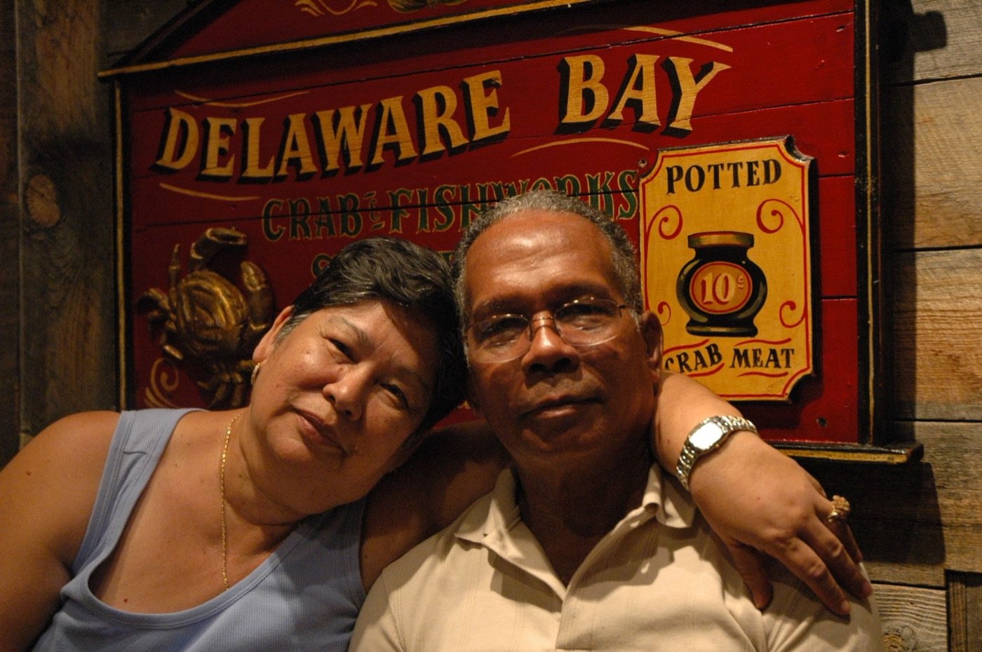 Pareja sonriendo frente a un letrero de Delaware Bay