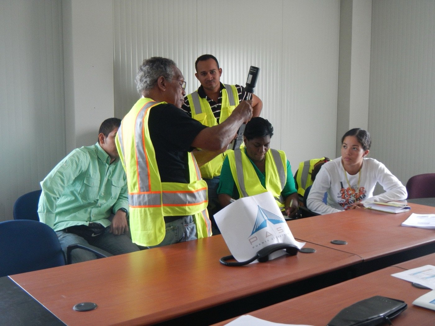 Equipo con chalecos reflectivos reunido alrededor de una mesa